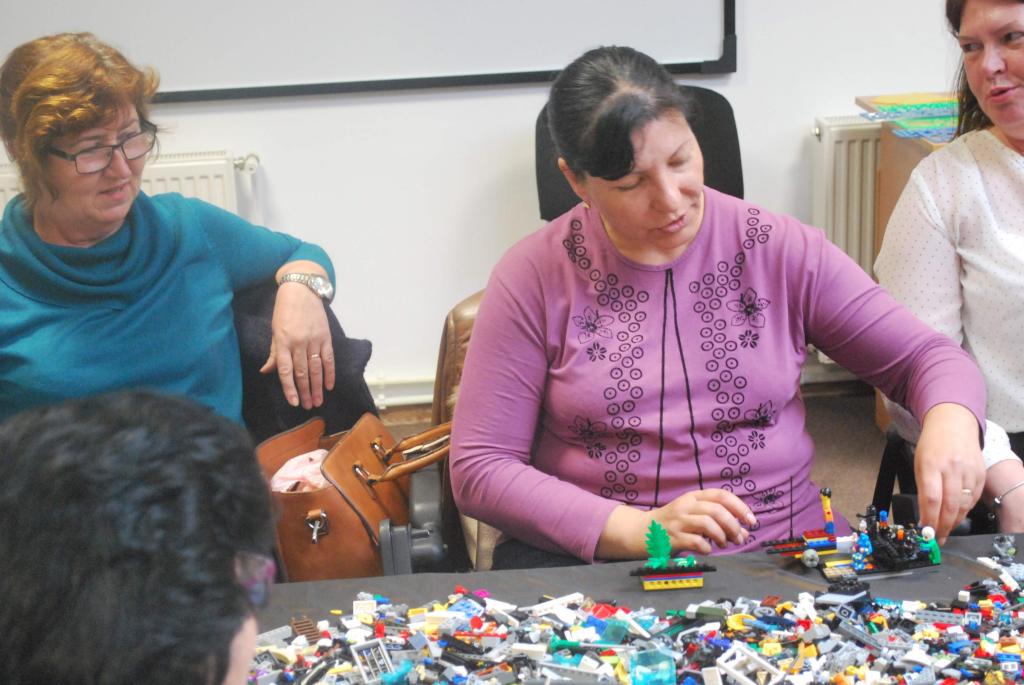 Profesoară construind un model din piese LEGO, alături de colege, la un atelier.